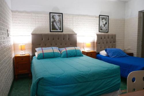 a bedroom with two beds with blue sheets and two lamps at Hostal Estadio Nacional in Santiago