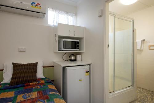 a small room with a bed and a microwave at Mineral Sands Motel in Maryborough