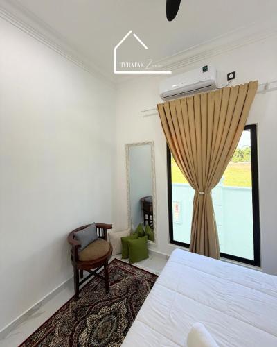 a bedroom with a bed and a window and a chair at Teratak Zara in Kota Tinggi
