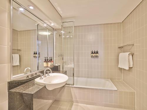 a bathroom with a sink and a bath tub at Rendezvous Hotel Sydney The Rocks in Sydney