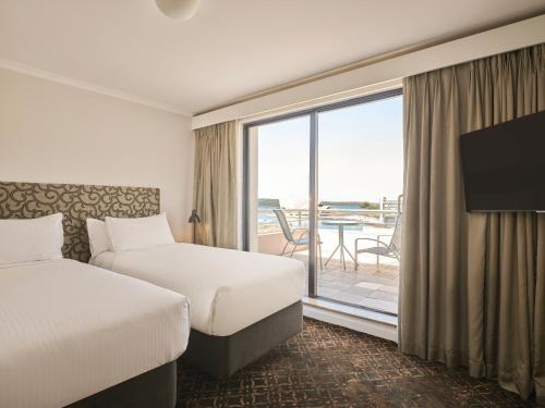 a hotel room with two beds and a balcony at Rendezvous Hotel Sydney The Rocks in Sydney