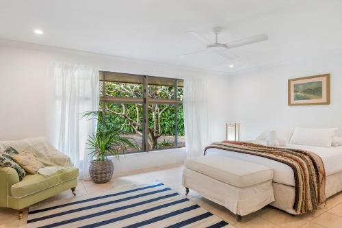 a bedroom with a bed and a chair and a window at Coorabell House in Ewingsdale