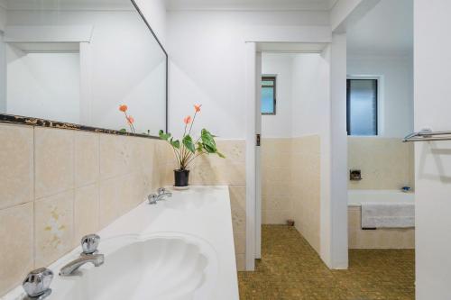 a bathroom with a white sink and a tub at Coorabell House in Ewingsdale