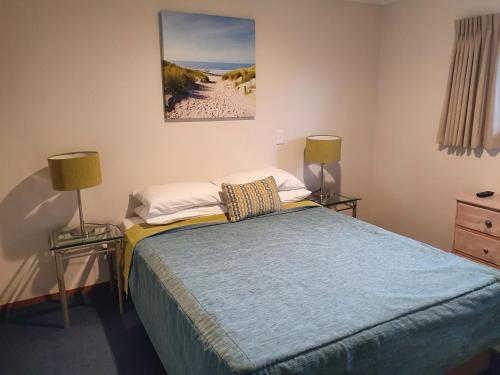 a bedroom with a bed with two lamps and a painting at Breakers Motel in Whangamata