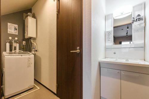 a small kitchen with a sink and a wooden door at UCHI Living Stay Sapporo Kikusui in Sapporo