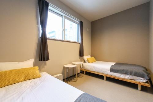 a bedroom with two beds and a window at UCHI Living Stay Sapporo Kikusui in Sapporo