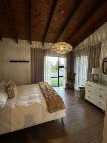 a bedroom with a large bed and a chandelier at Oubaai golf eatate in Herolds Bay