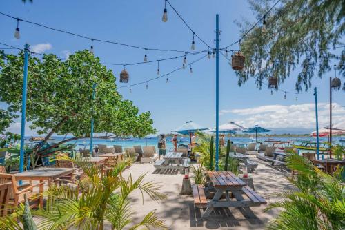 a beach with picnic tables and chairs and the ocean at Bale Sampan Boutique Bungalows in Gili Trawangan