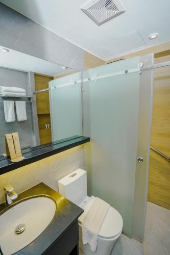 ein Badezimmer mit Toilette, Waschbecken und Spiegel in der Unterkunft Venus Parkview Hotel in Baguio City