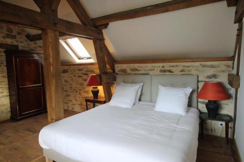 a bedroom with a white bed with two lamps at La pommeraie in Château-Chervix