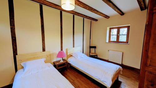 a bedroom with two beds and a pink lamp at Maison des bois in Château-Chervix