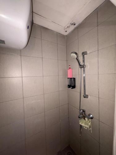 a shower in a bathroom with a pink bottle on the wall at Studio Bogor Icon Apt wifi&pool in Kedunghalang