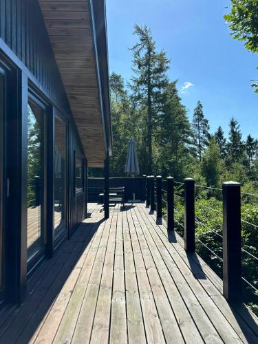 a wooden deck with an umbrella next to a building at Forest Cabin Overlooking Bryrup Langsø in Silkeborg