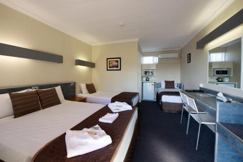 a hotel room with a bed and a kitchen at Mineral Sands Motel in Maryborough