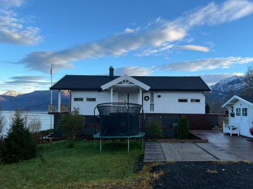 a white house with a chair in front of it at Northern Lights View Cabin With Big Veranda in Ballangen