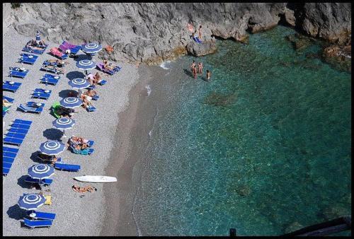 a group of people laying on a beach with umbrellas at Residence Due Torri in Maiori