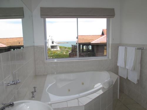 a white bathroom with a tub and a window at Belle Mer Guest House in Pringle Bay