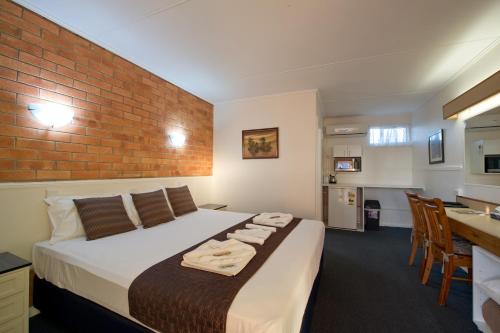 1 dormitorio con cama y pared de ladrillo en Mineral Sands Motel en Maryborough