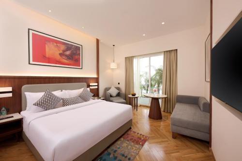 a hotel room with a bed and a chair at Skywings Sarovar Portico Mathura in Mathura