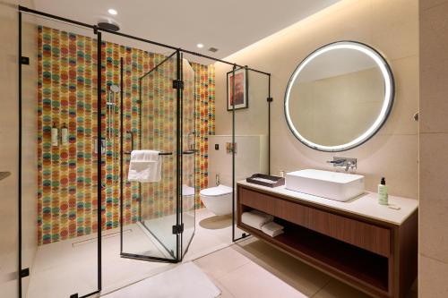 a bathroom with a shower and a sink and a mirror at Skywings Sarovar Portico Mathura in Mathura
