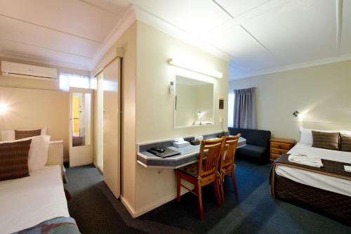 a hotel room with a sink and a bed and a desk at Mineral Sands Motel in Maryborough
