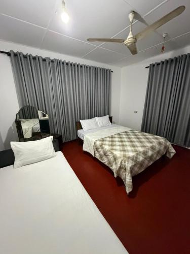 a bedroom with two beds and a ceiling fan at GMW Sanduni hotel & villa in Matara