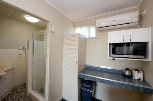una pequeña cocina con armarios blancos y microondas en Mineral Sands Motel en Maryborough