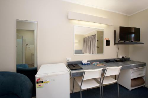 a room with a desk with two chairs and a mirror at Mineral Sands Motel in Maryborough