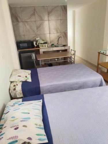 a room with two beds and a kitchen with a sink at Centro de Tacna quinto piso in Tacna