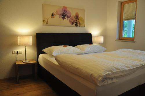 um quarto com uma cama com lençóis brancos e 2 candeeiros em Bergchalet Rauch em Arzl im Pitztal