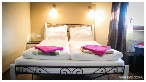 a bed with white sheets and pink pillows on it at Pokoje BALDI Benelux in Skoczów