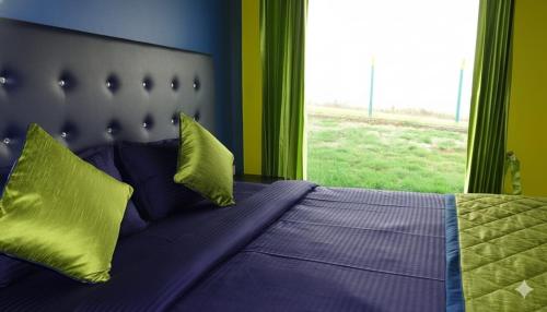 a bedroom with a bed with yellow pillows and a window at The Bowers Chalet Private Campfire & Lawn BBQ, WIFI, Breakfast Hill Top 360 degree view in Ooty