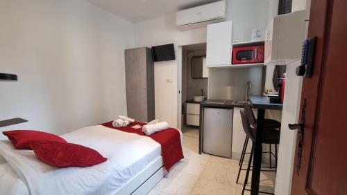 a bedroom with a bed with red pillows and a kitchen at Sweet Home Marceau - 6 studios hyper centre proche de la mer et du palais in Cannes