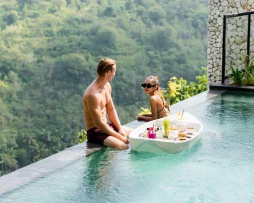 two men sitting in a swimming pool with a bath tub at MAUA Nusa Penida Bali in Nusa Penida