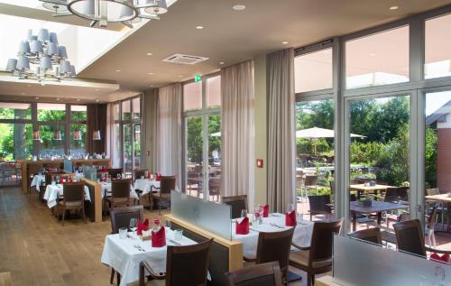 a restaurant with tables and chairs and windows at Jammertal Resort in Datteln