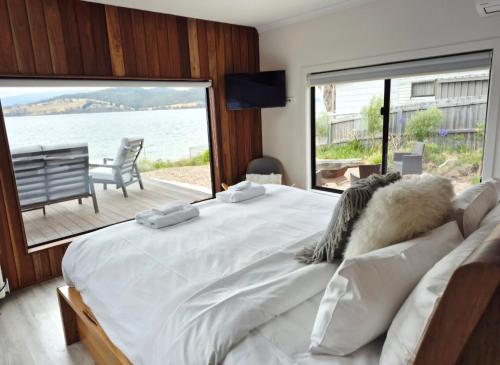 a bedroom with a large bed with a view of the water at The Nebraska Retreat in Dennes Point