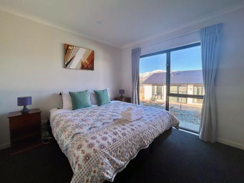 a bedroom with a bed and a large window at Matariki Star in Lake Tekapo