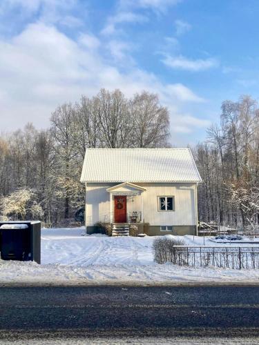 a white barn with a red door in the snow at Cosy House Surrounded By Nature in Diö