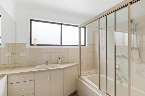 a bathroom with a tub and a sink and a shower at Andrea and Nigel's Beach House in Cape Woolamai