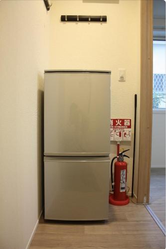 a refrigerator in a room with a fire extinguisher at Jasnine House in Tokyo