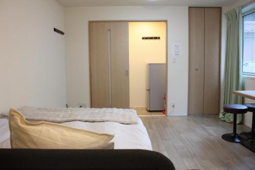 a bedroom with a bed and a door to a refrigerator at Jasmine House in Tokyo