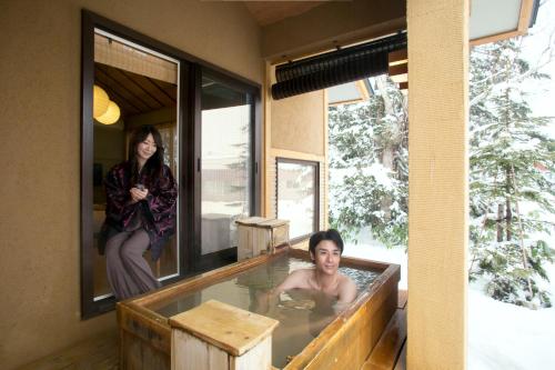 a woman sitting in a hot tub in a house at Morinoryotei Biei in Biei
