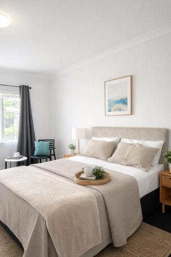 a white bedroom with a large bed with a table at Banksia Motel Bass Hill in Bass Hill