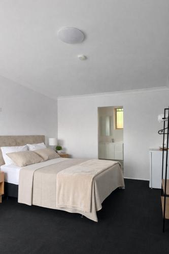 a white bedroom with a large bed in a room at Banksia Motel Bass Hill in Bass Hill