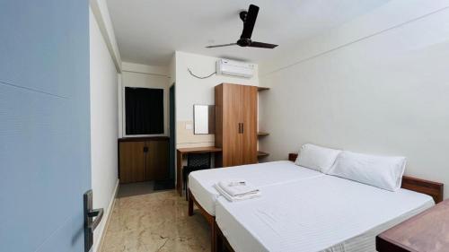 a bedroom with a white bed and a desk at Jo Homes Apartments in Alwaye