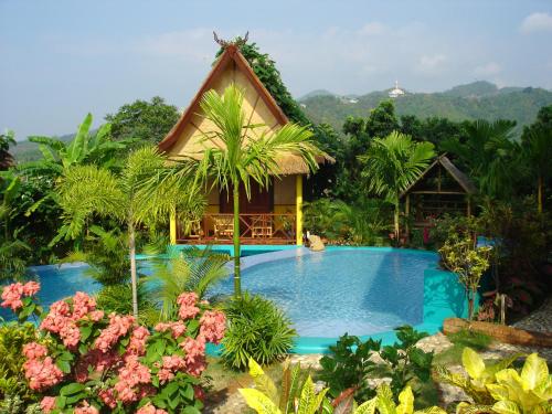 een resort met een groot zwembad in een tuin bij Old Tree's House ThaTon in Mae Ai