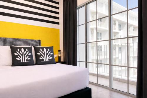 a bedroom with a white bed and a large window at Stallionz Ipoh by ANGO in Ipoh