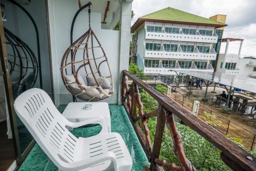 a balcony with two white chairs and a building at Mam Kaibae Hotel in Ko Chang