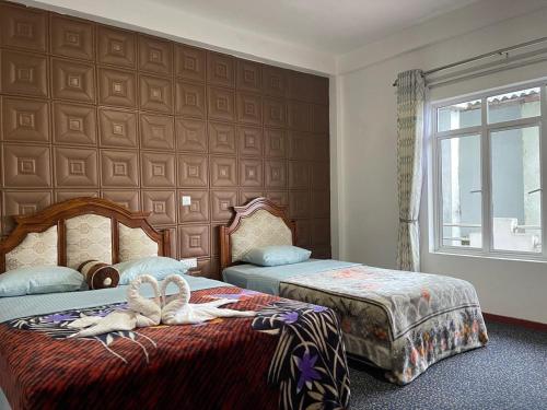 a bedroom with two beds and a large wall at Namadi Nest Nuwara Eliya in Nuwara Eliya