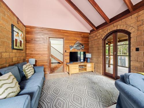 a living room with a blue couch and a television at Kookaburra Retreat - Dog Friendly - Forest View in Gnarabup